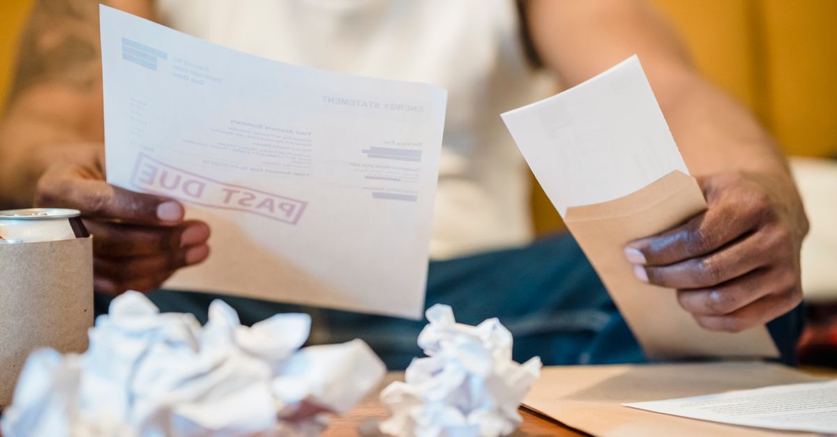 A person reviewing a utility bill and energy statement at a wooden desk.