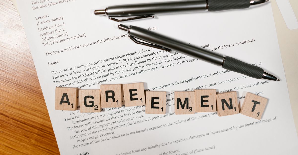 Close-up of hands signing a rental agreement document with a pen