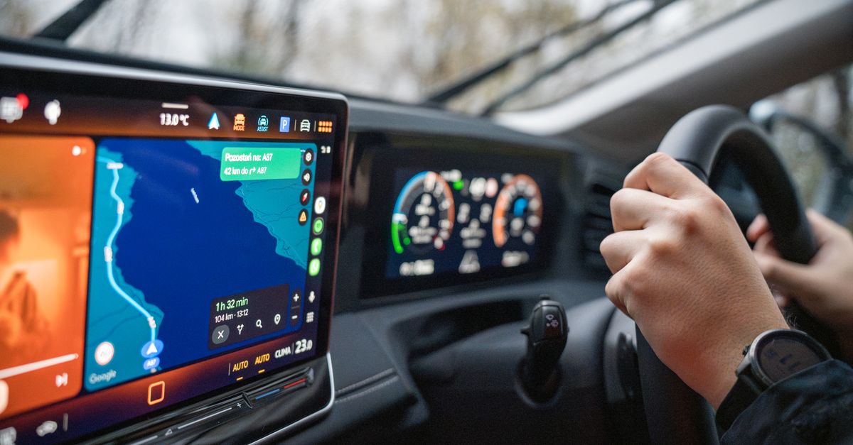 Close-up of hands navigating a vehicle touchscreen infotainment display