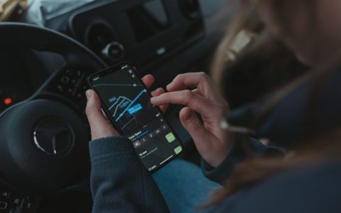 Driver checking a smartphone inside a modern vehicle cabin