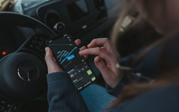 Driver checking a smartphone inside a modern vehicle cabin
