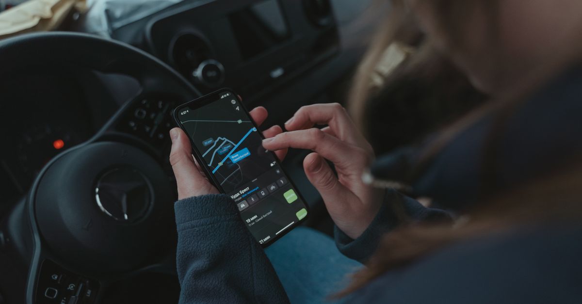 Driver checking a smartphone inside a modern vehicle cabin