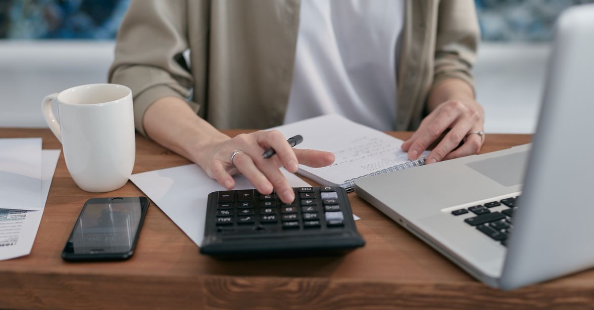 Homeowner calculating monthly utility expenses using a laptop and calculator