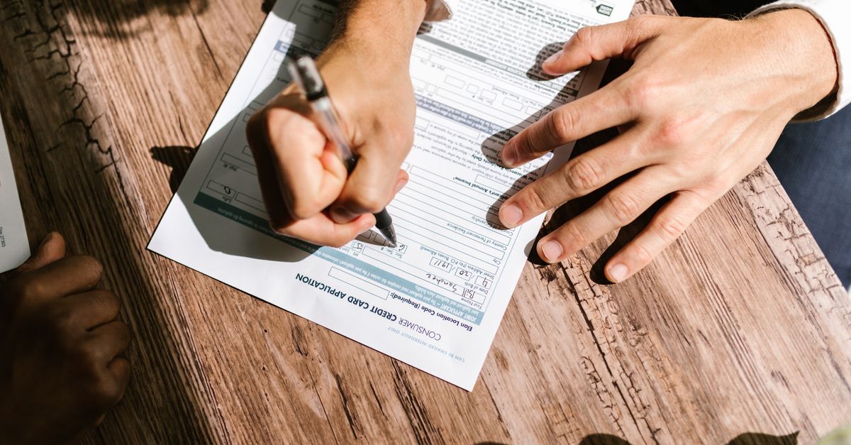 Close-up of hands filling out a government vital statistics application form with a pen.
