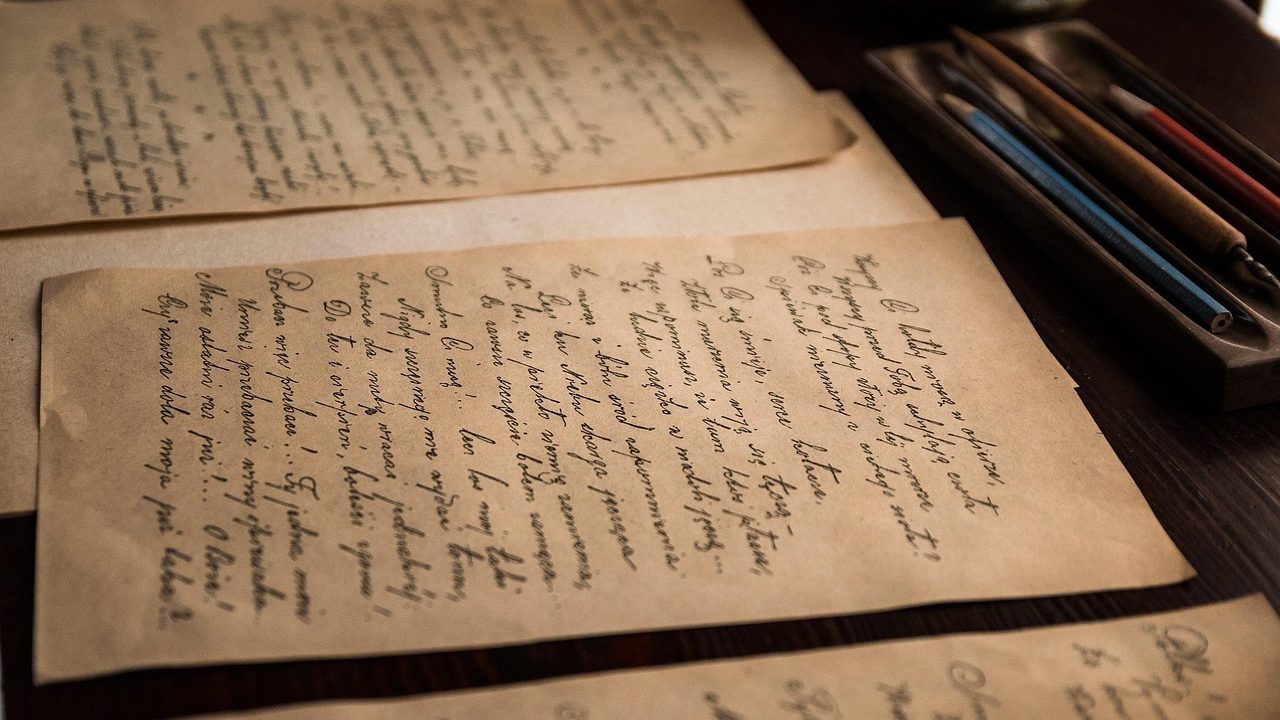 A person reviewing old historical documents and property maps at a wooden desk