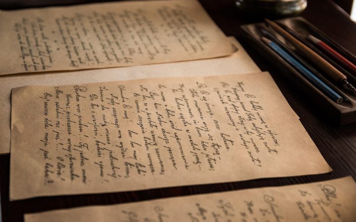 A person reviewing old historical documents and property maps at a wooden desk