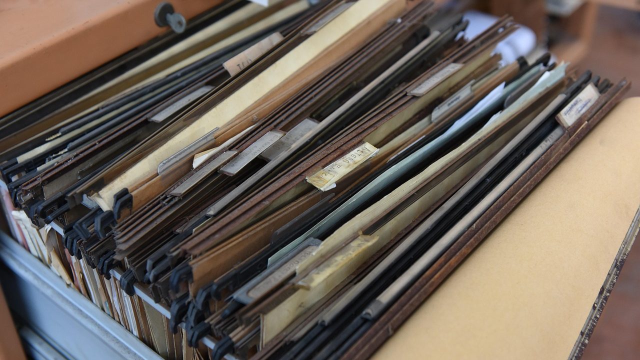 Close-up of hands organizing official government forms and documents on a wooden desk.