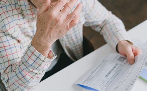 Close-up of a consumer reviewing an electric bill statement at a wooden desk.