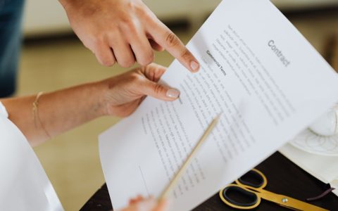 Corporate professional reviewing a compensation contract at a wooden desk.