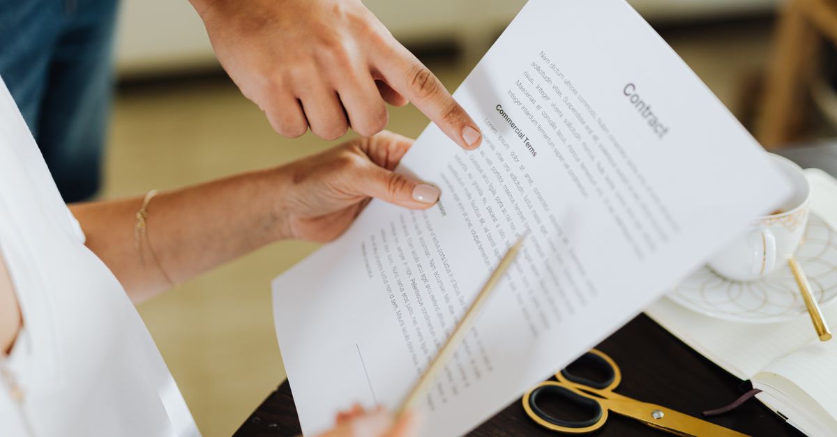 Corporate professional reviewing a compensation contract at a wooden desk.