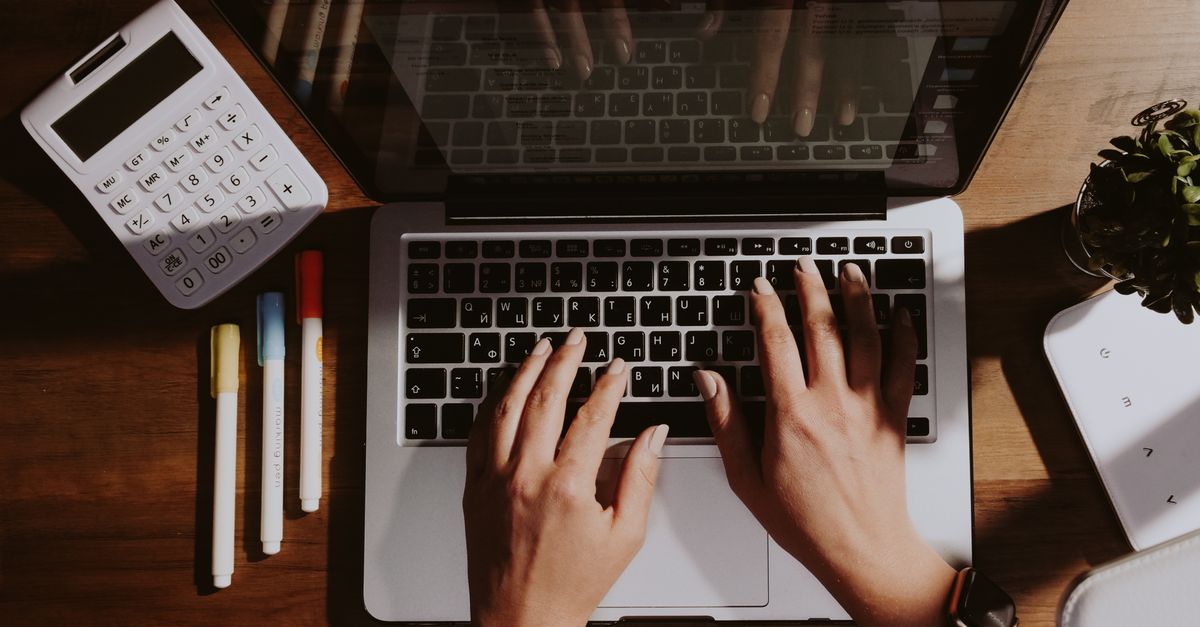 Person using a laptop and calculator to budget household medical expenses