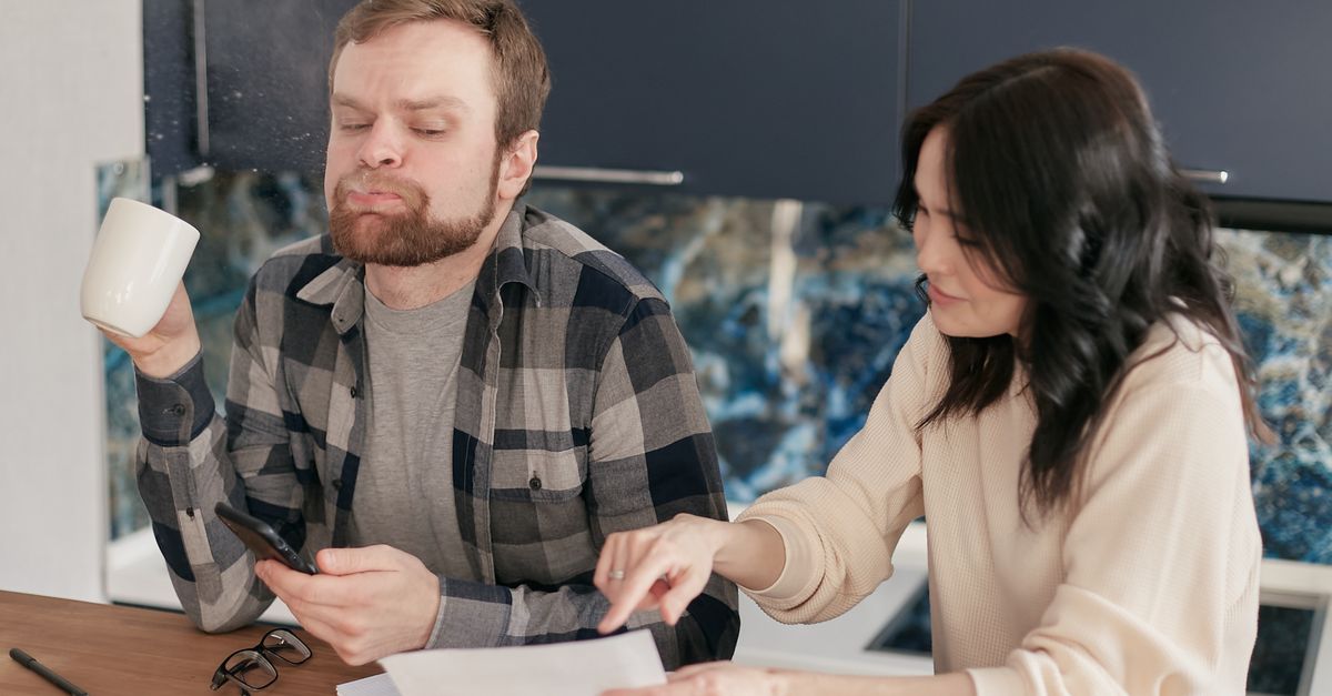Homeowner reviewing electricity costs and appliance energy consumption at a kitchen counter.