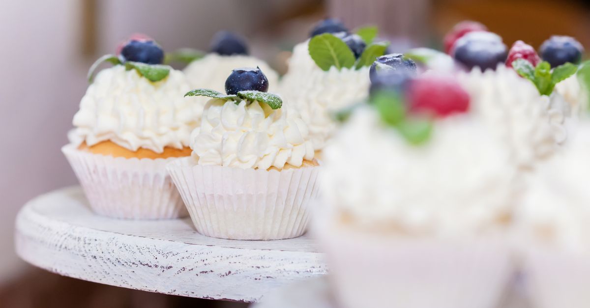 Parent and child baking and decorating birthday cupcakes in a bright home kitchen