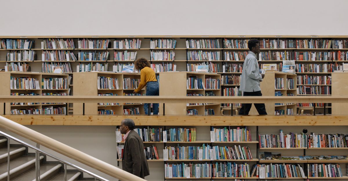 A parent and child looking at books together in a public library.
