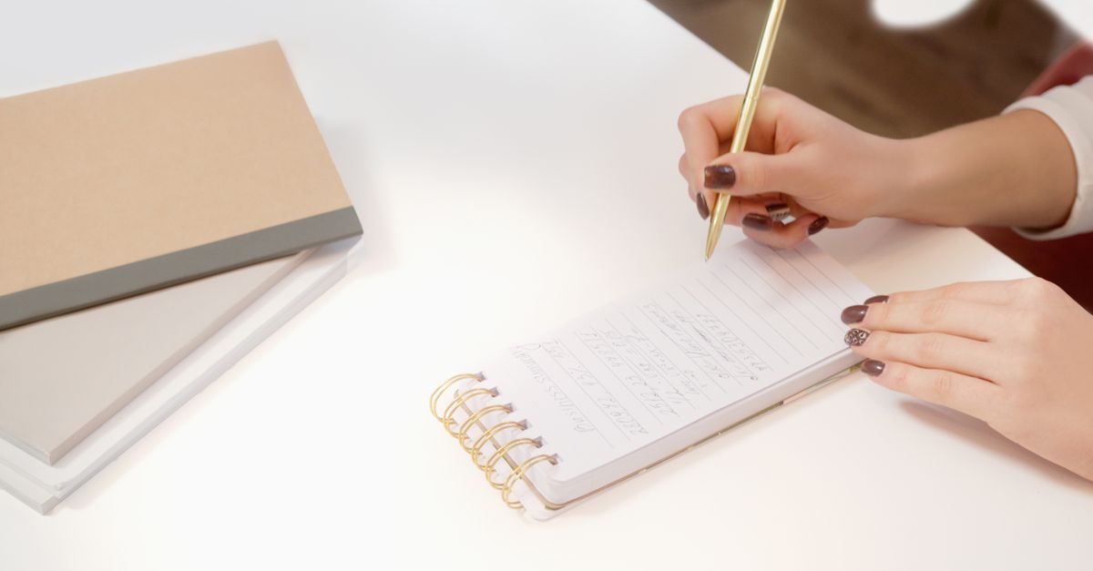 A person writing recovery notes inside a physical notebook with a pen.