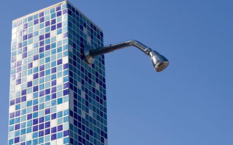 A modern chrome shower head installed in a clean tiled bathroom.