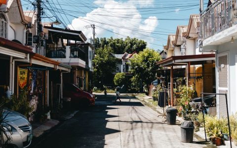 A clean, well-maintained mobile home community street under a bright daytime sky.