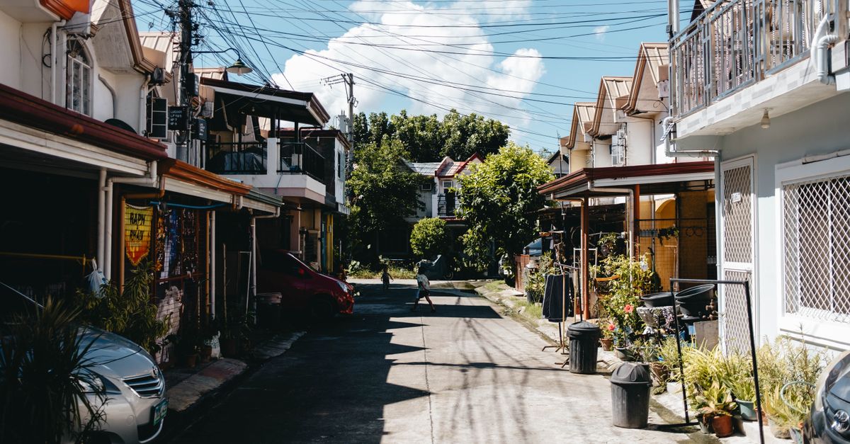A clean, well-maintained mobile home community street under a bright daytime sky.