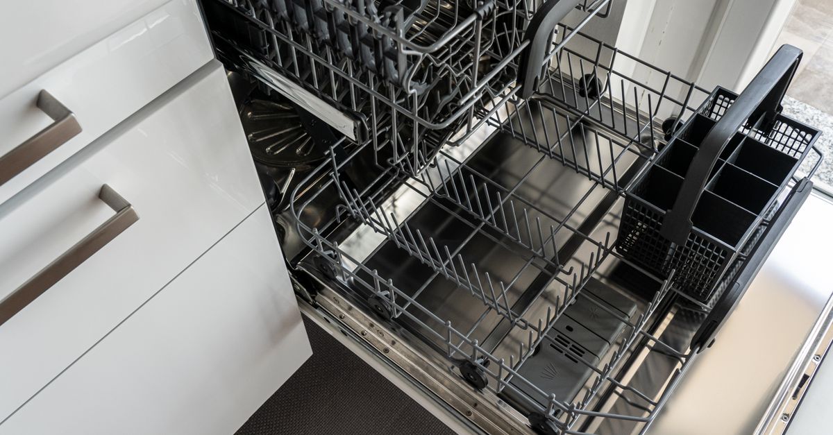 Kitchen contractor installing a built-in dishwasher beneath quartz countertops.