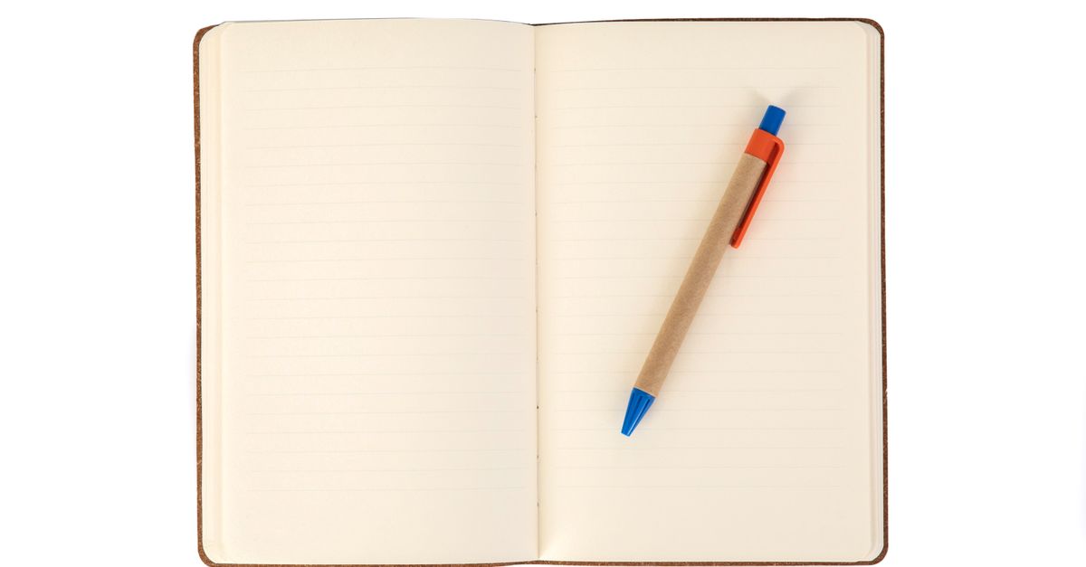 Open notebook with handwritten text and a metal pen on a desk