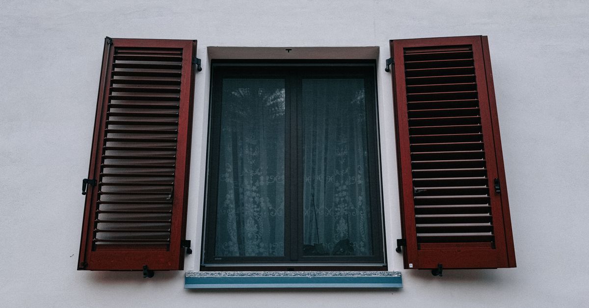 Close-up of solid wood plantation shutters installed inside a bright living room window.