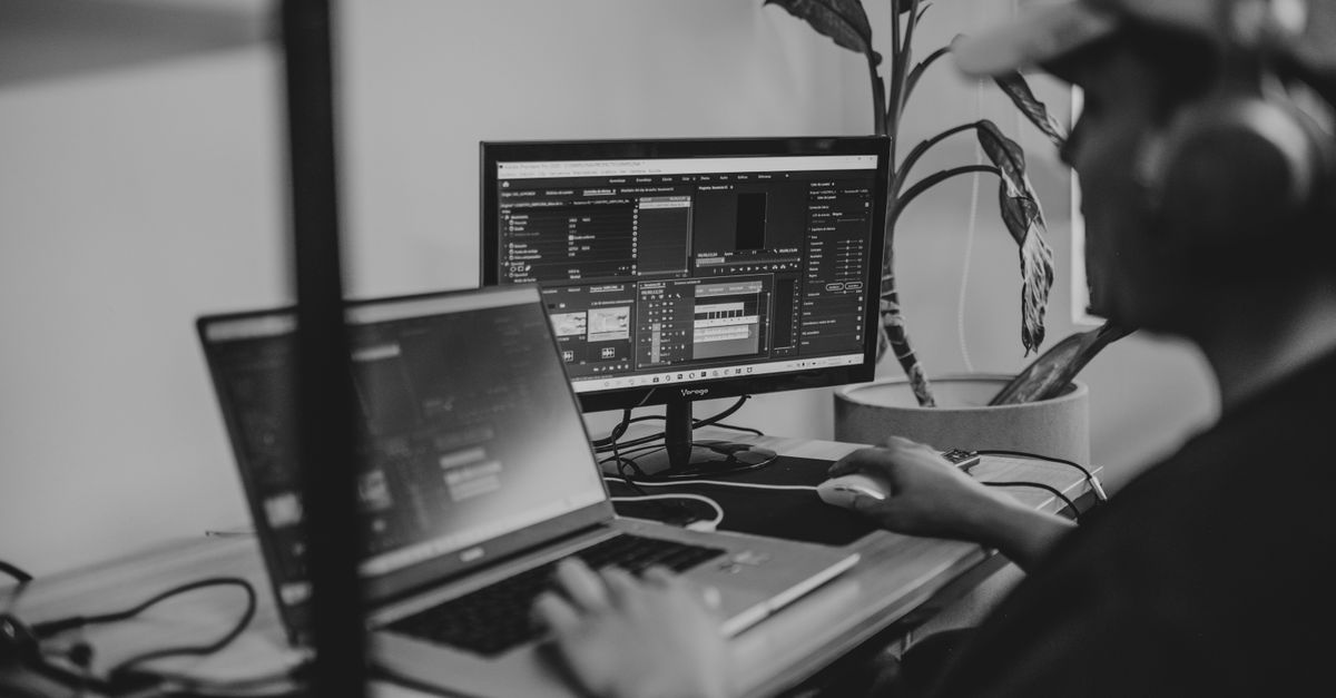 A remote worker typing on a laptop with dual portable monitors attached.