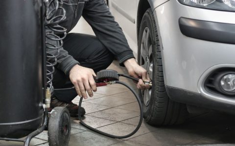 Mechanic inspecting a shop air compressor in a garage