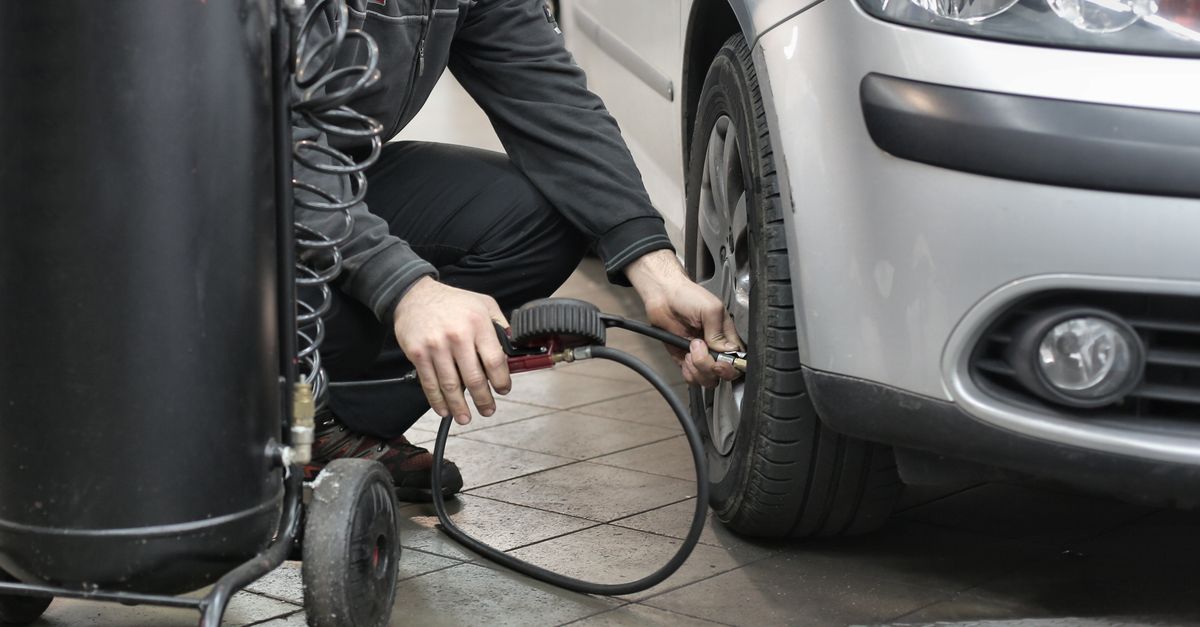 Mechanic inspecting a shop air compressor in a garage