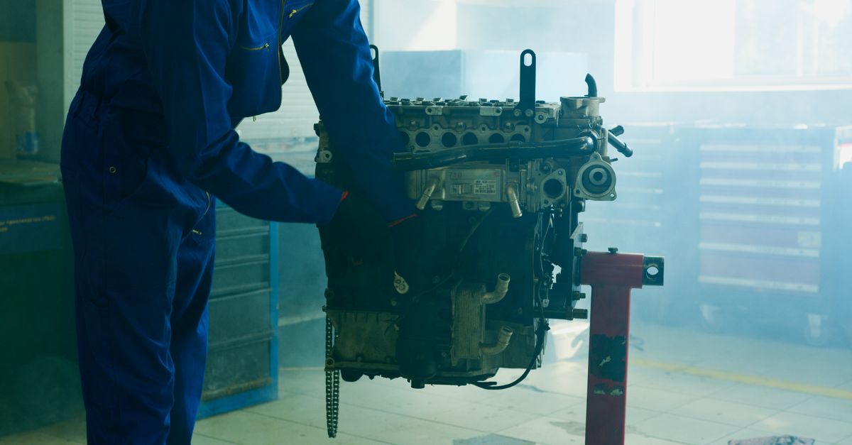 A technician inspecting the guide bar and chain of a gas chainsaw on a workbench.
