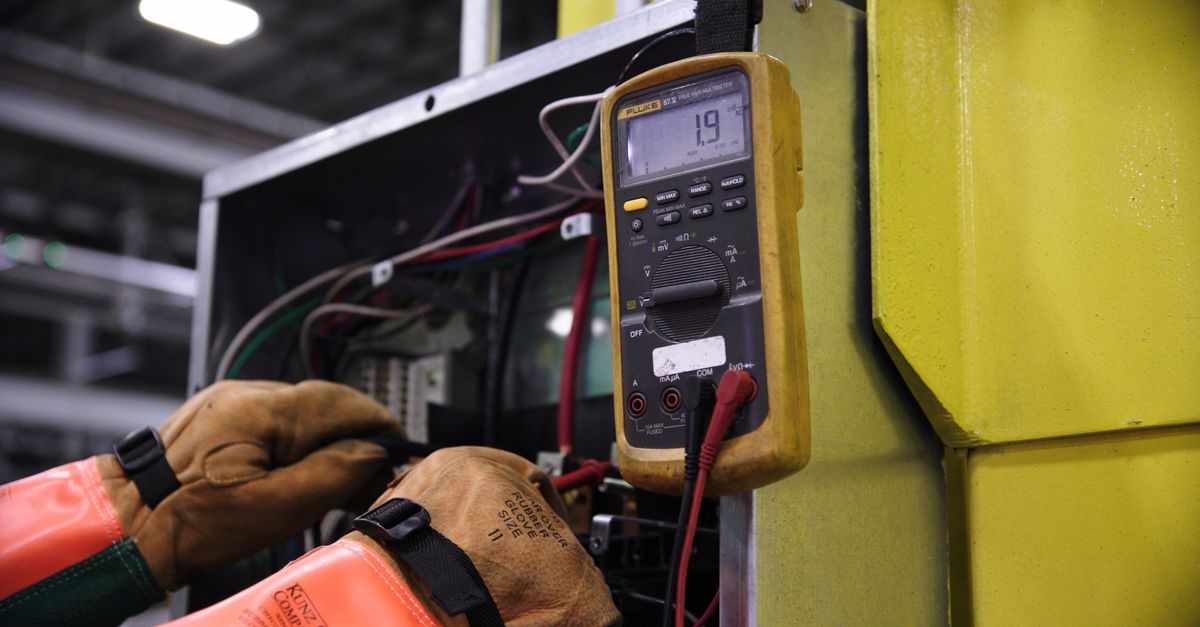 Technician checking electrical panel wiring with digital test probes.
