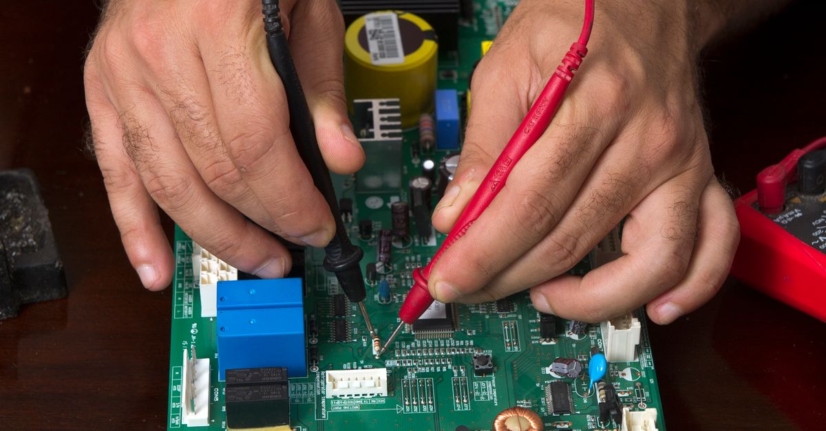 Technician testing electronic components and wiring on a circuit board.