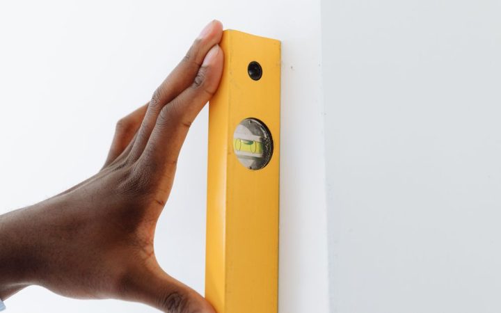 A carpenter checking alignment with a green beam laser level on a residential job site.