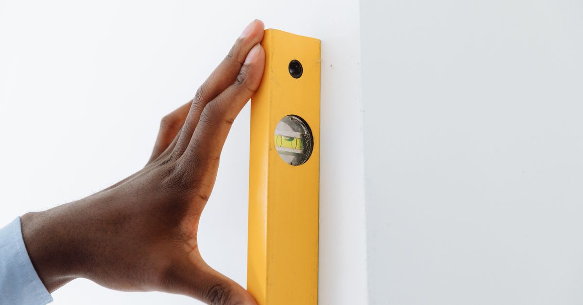A carpenter checking alignment with a green beam laser level on a residential job site.