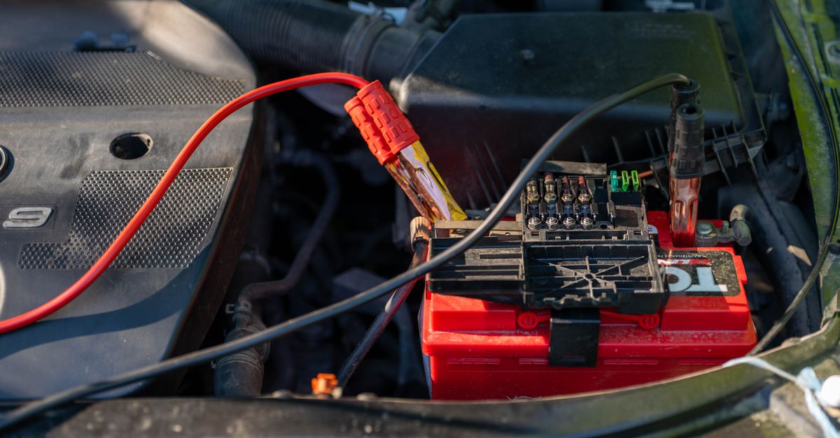 Mechanic attaching jumper cables to a car battery