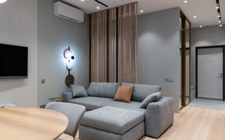 A portable air conditioner unit standing in a modern apartment living room near a window.