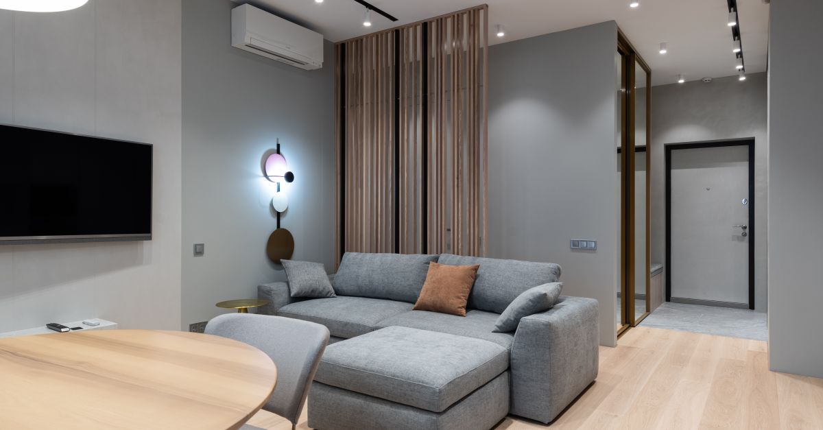 A portable air conditioner unit standing in a modern apartment living room near a window.