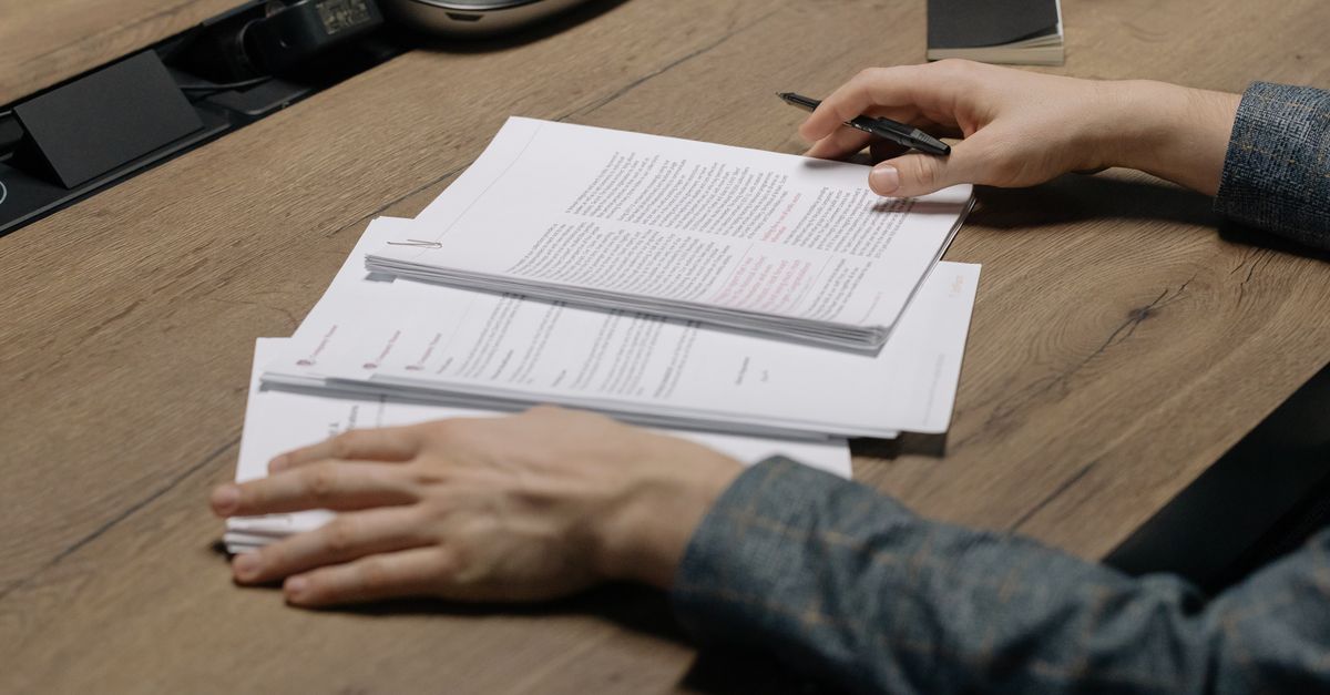 Professional reviewing printed documents and project briefs at a desk