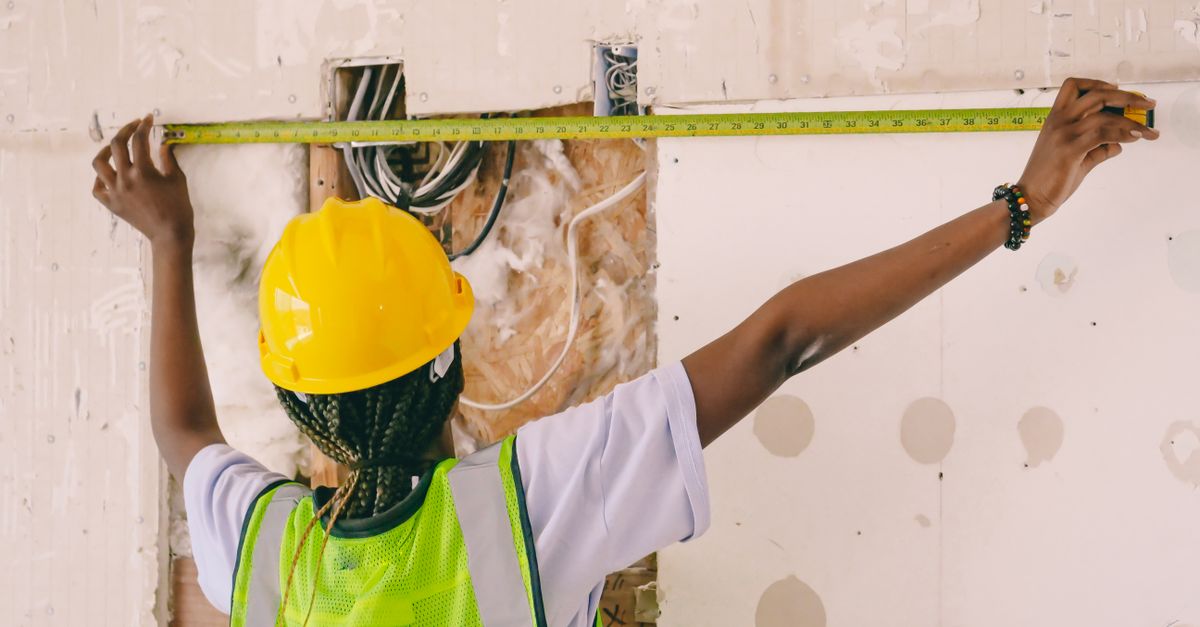 Construction worker installing plywood shear bracing on crawlspace cripple walls.
