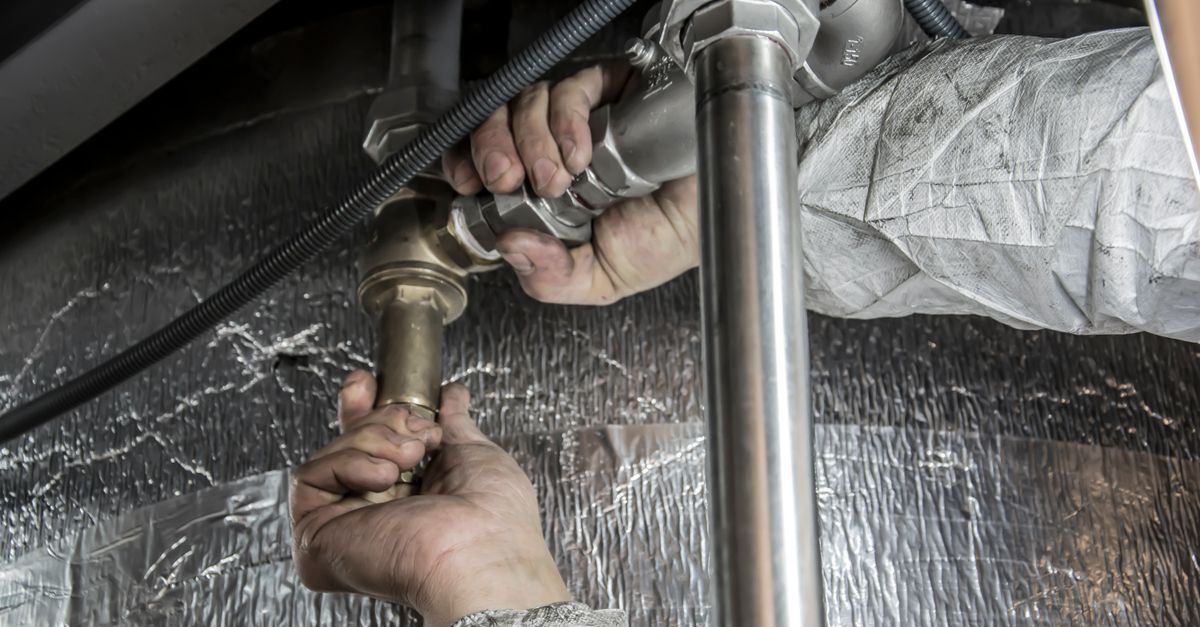 Plumber working on residential water filtration pipes in a utility room