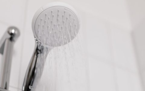 Close up of a modern chrome showerhead in a tiled bathroom
