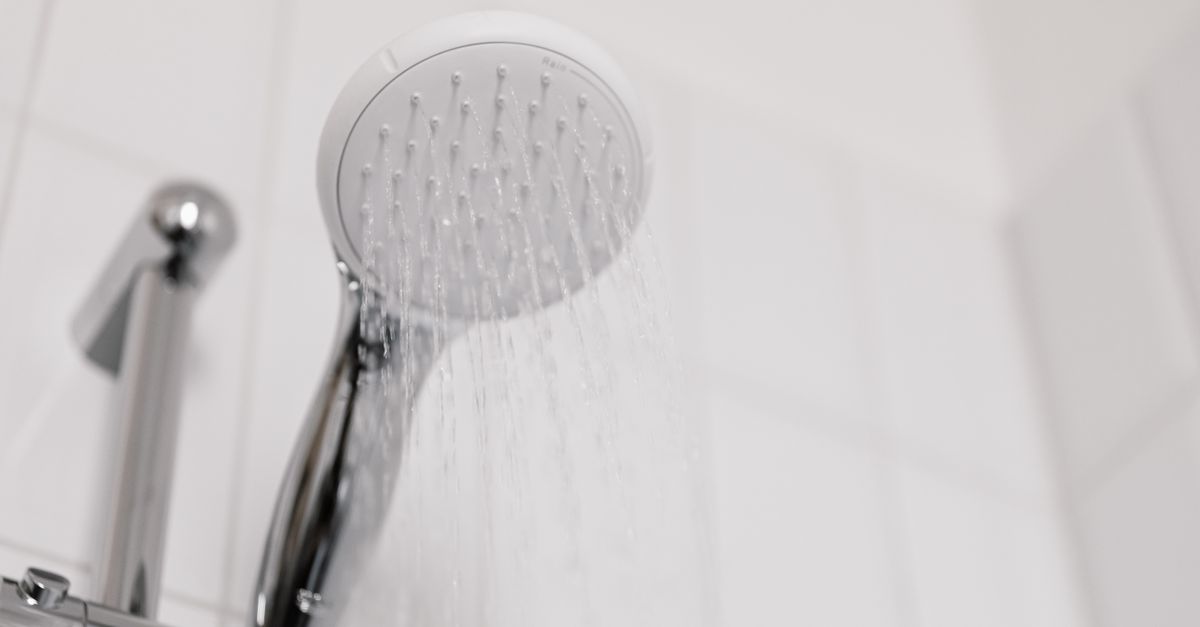 Close up of a modern chrome showerhead in a tiled bathroom