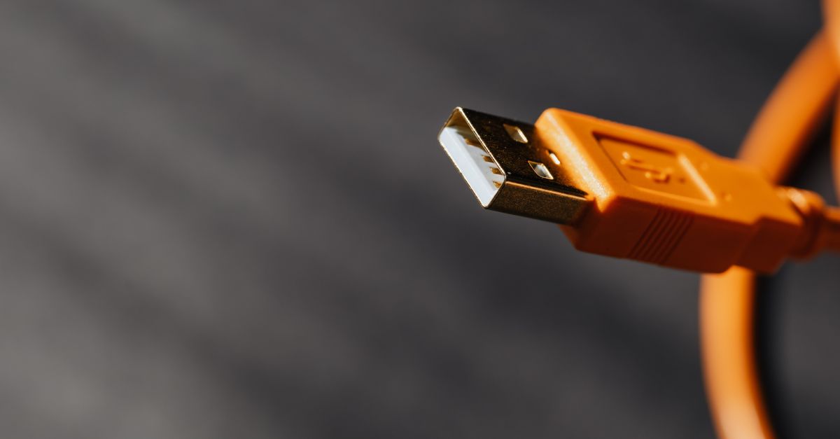 Close-up of hands plugging a high-speed data cable into a device port.