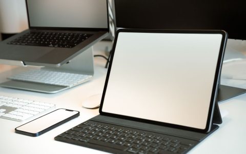 A modern workspace featuring a laptop connected to a tablet via a USB cable.