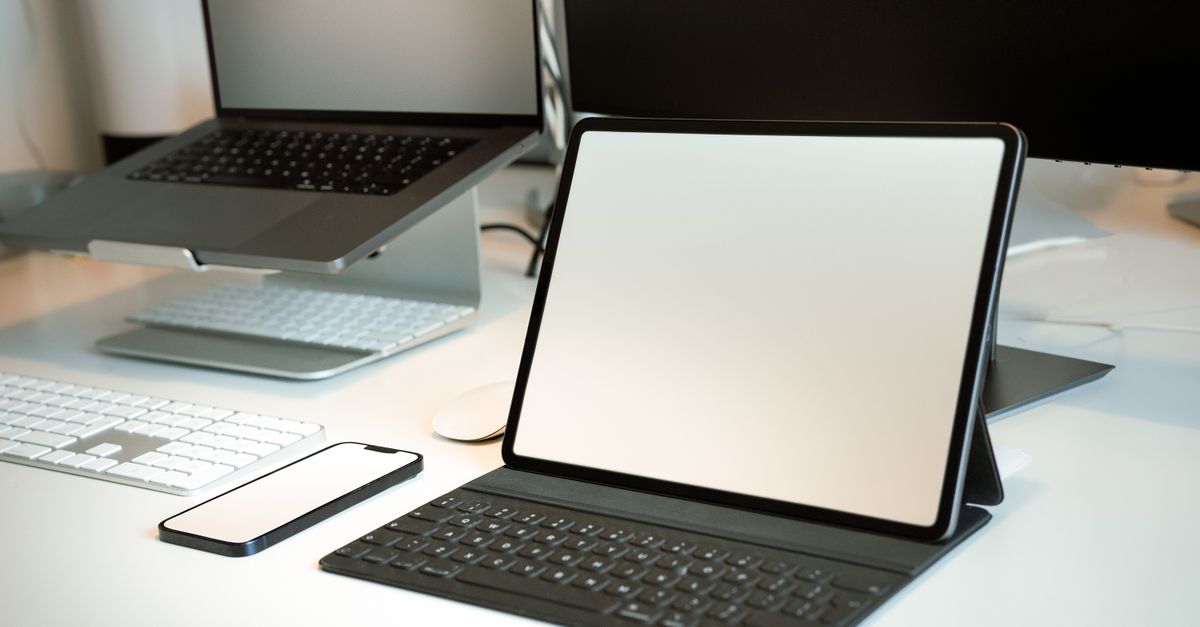 A modern workspace featuring a laptop connected to a tablet via a USB cable.