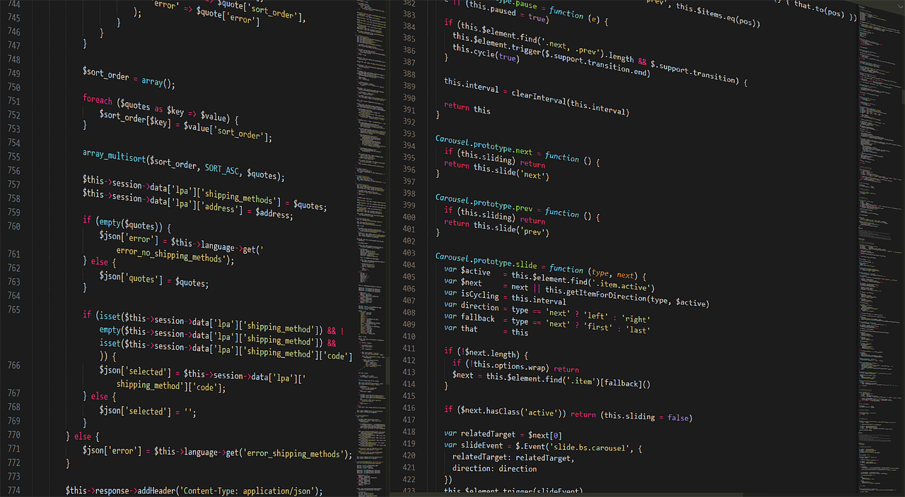 Software developer looking at code on a dual monitor workstation