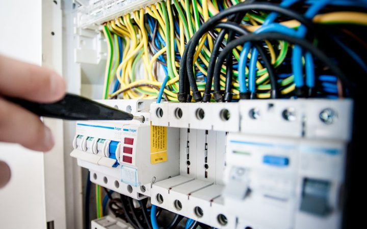 Electrician inspecting a home electrical service panel with a multimeter